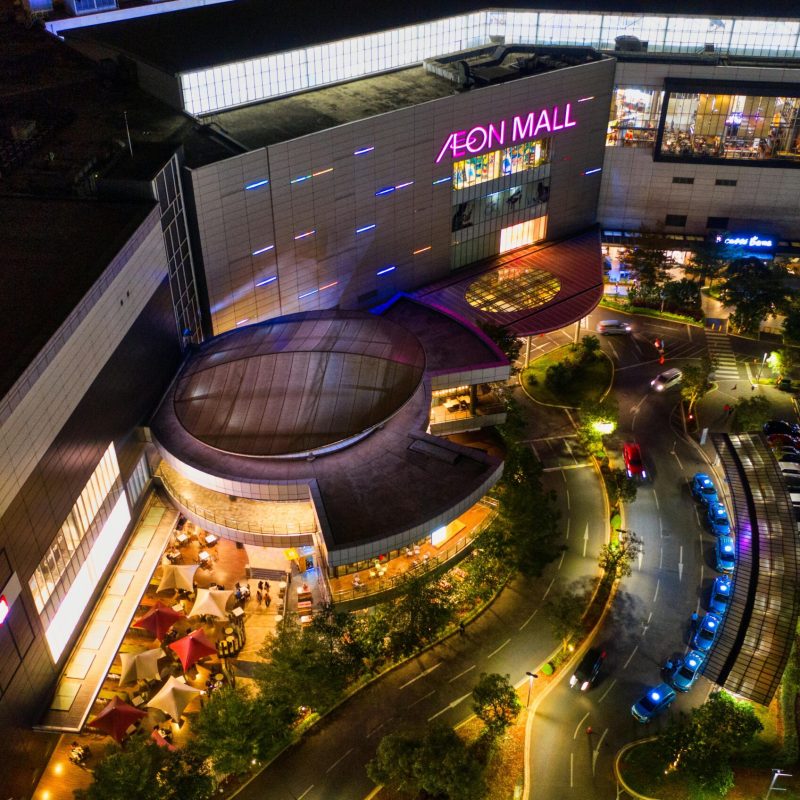Illuminated aerial view of Aeon Mall in Banten, Indonesia, featuring a bustling parking lot at night.