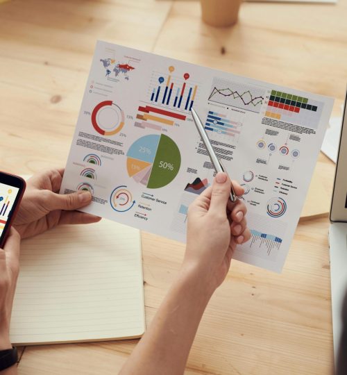 Team members analyze charts during a business meeting with laptops and smartphones.