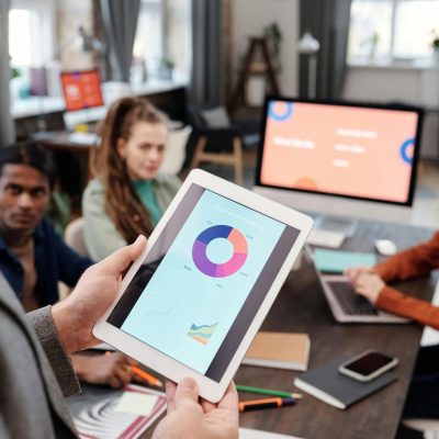 Colleagues reviewing business data on a tablet in a modern office setting.