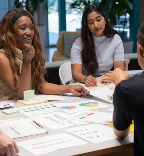 Group of coworkers discussing marketing strategies around a table in a contemporary workspace.